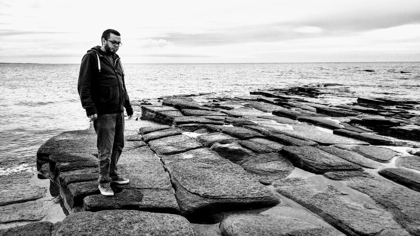 Me stood on the beach in Northumberland, on layers of rocks.
